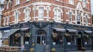 A corner building with "The Kings Arms" sign, featuring a traditional brick facade with white trim, multiple windows, and outdoor seating. - The Kings Arms (London)