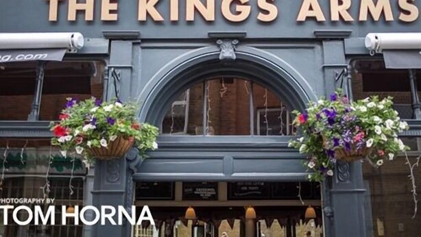 The exterior of The Kings Arms, a pub with a classic facade, two flower baskets on either side of the entrance, and a sign above the door. - The Kings Arms (London)
