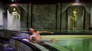 A man relaxing in a hot spring with statues in the background. - Grand Jambi (Jambi)