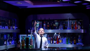 A bar area with shelves of liquor bottles and a bartender. - Grand Jambi (Jambi)