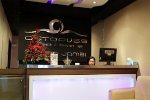 A reception desk with a sign for 'Optopuss Health & Executive Spa' and a decorative floral arrangement. - Grand Jambi (Jambi)