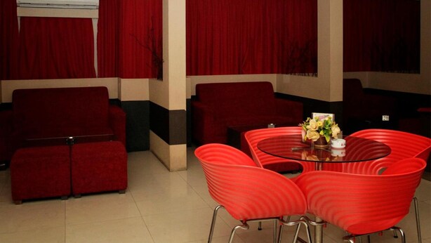 A room with a red sofa, red armchairs, and a glass table with a vase of flowers. - Grand Jambi (Jambi)