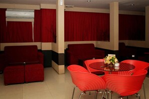 A room with a red sofa, red armchairs, and a glass table with a vase of flowers. - Grand Jambi (Jambi)