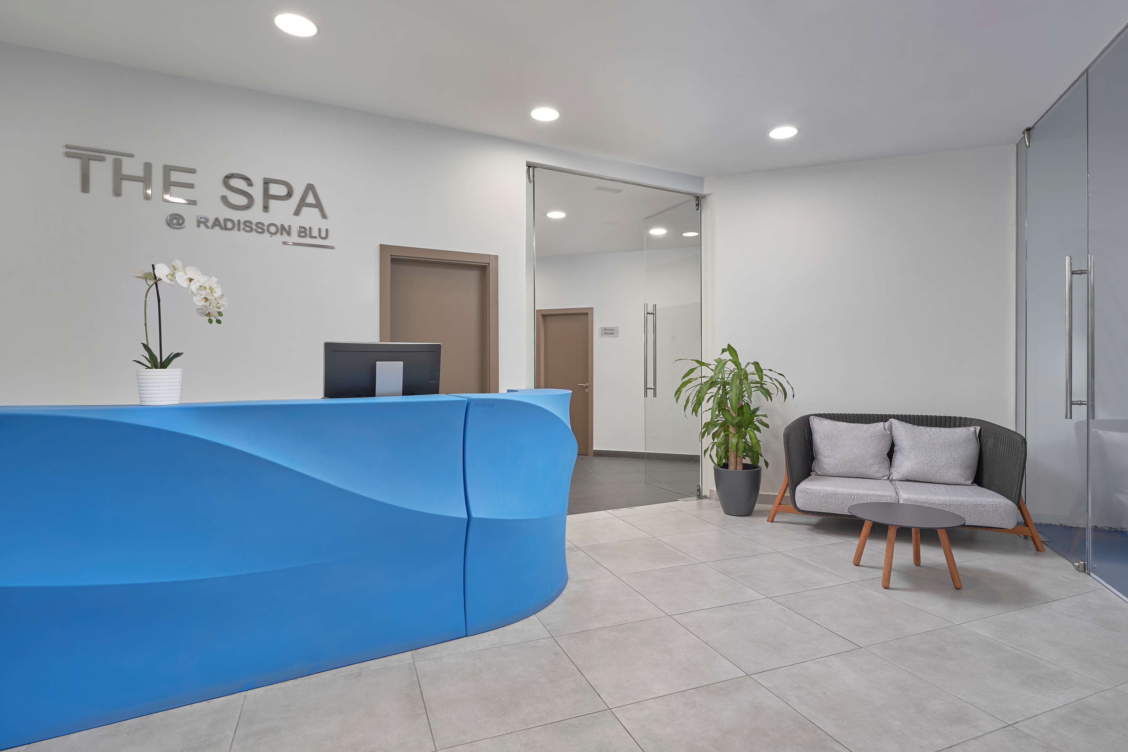 A reception area with a blue counter, a sofa, and a potted plant.