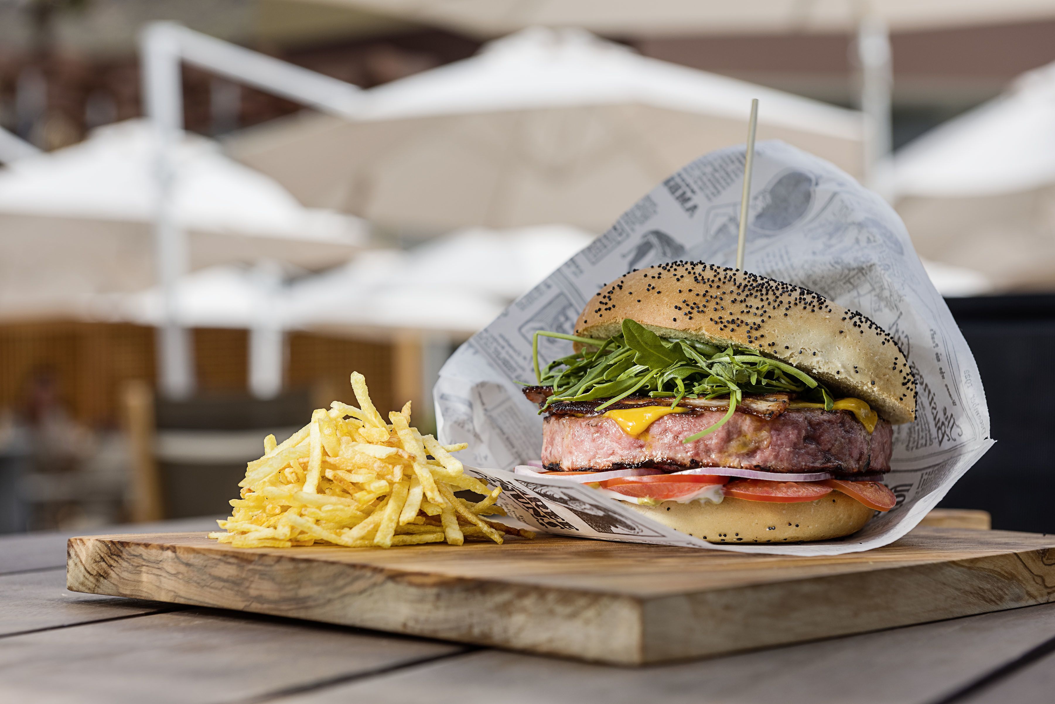 A burger with fries on a wooden board.