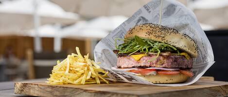 A burger with fries on a wooden board.