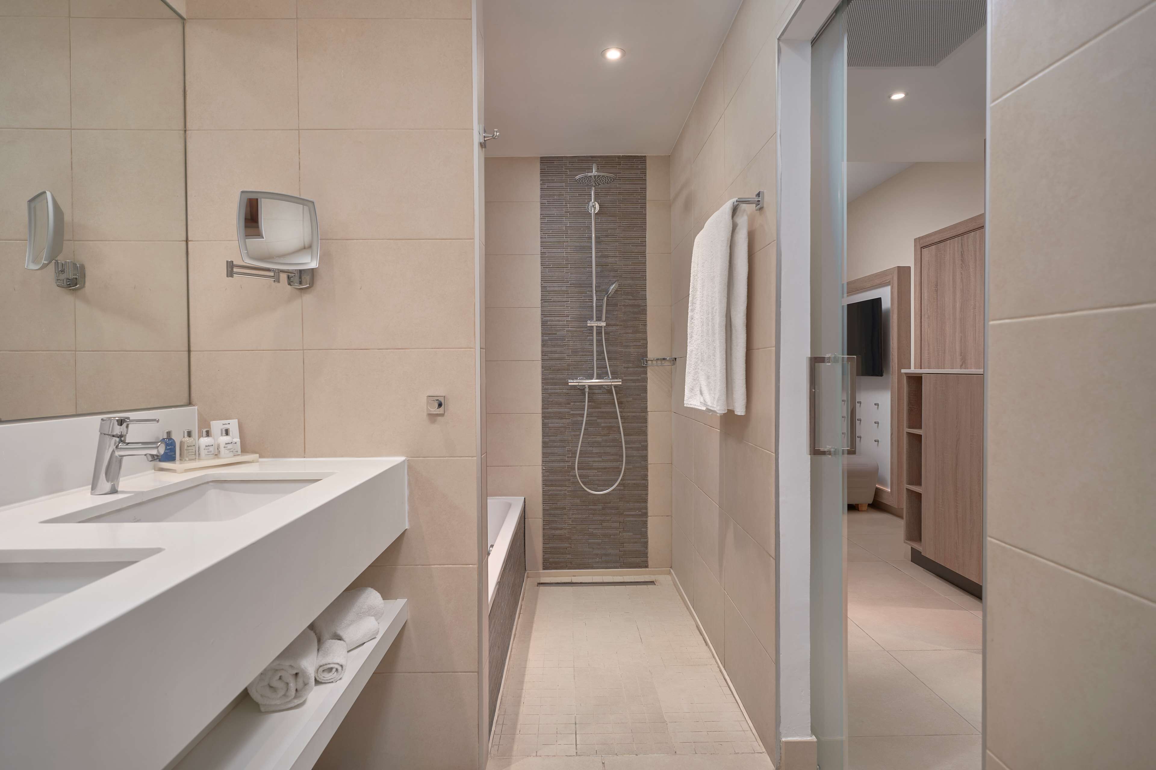 Un baño moderno con un espejo grande, dos lavamanos, ducha y vestidor.