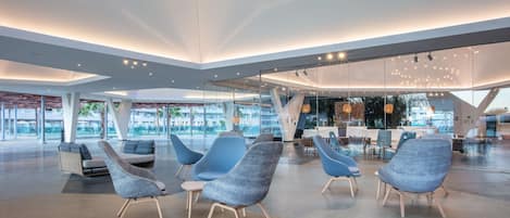 Un vestíbulo moderno con mobiliario contemporáneo, paredes de vidrio y un diseño espacioso.