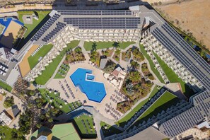 Vue aérienne d’un hôtel doté d’une piscine centrale, de nombreux balcons et d’espaces paysagers aménagés tout autour.