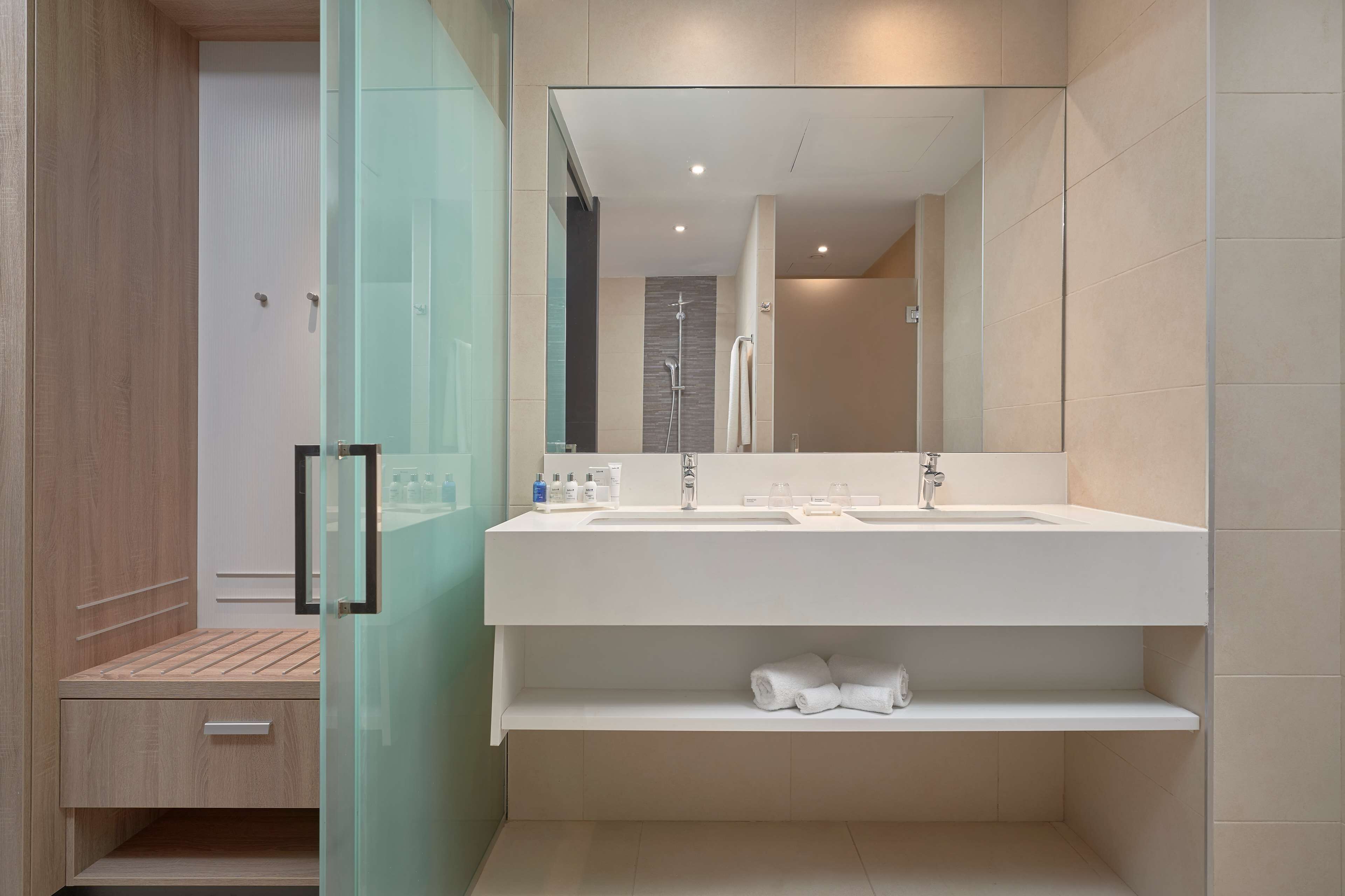 Un baño moderno con un espejo grande, dos lavamanos y una zona de ducha.