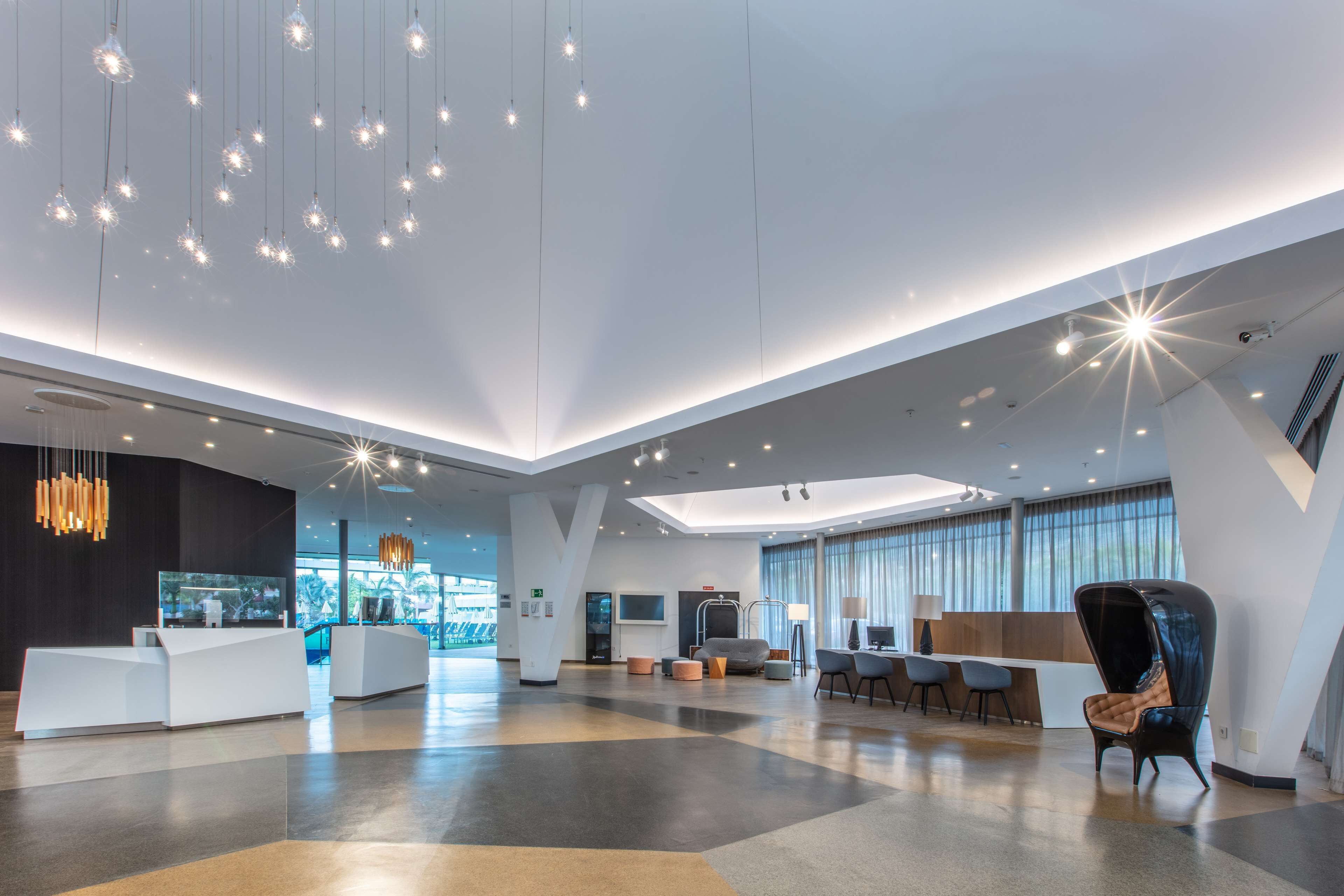 Eine geräumige Lobby mit einer Rezeption, einer Sitzecke und großen Fenstern.