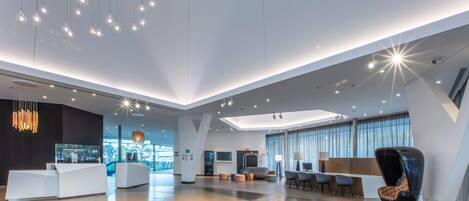 A spacious lobby with a reception desk, seating area, and large windows.