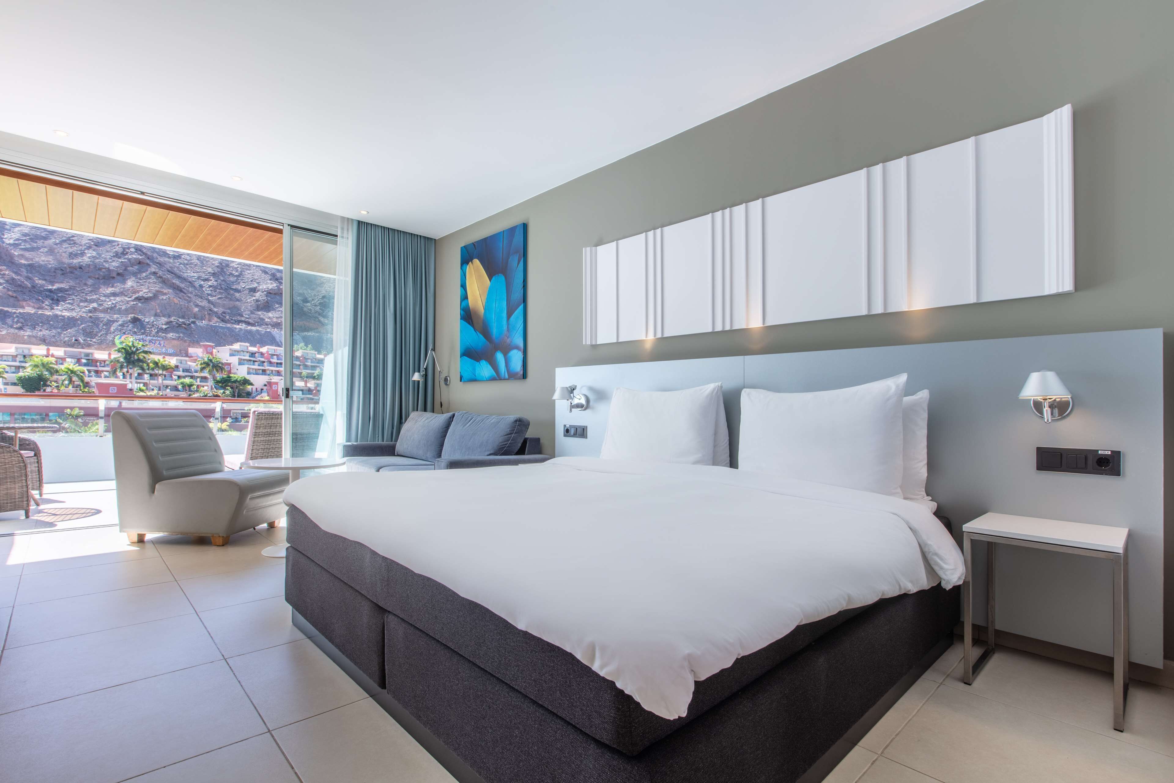 Et moderne hotelværelse med en stor seng, et opholdsområde med udsigt og en balkon.