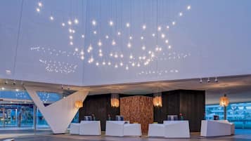 A modern reception area with multiple white reception desks, a wooden textured wall, and hanging light fixtures.