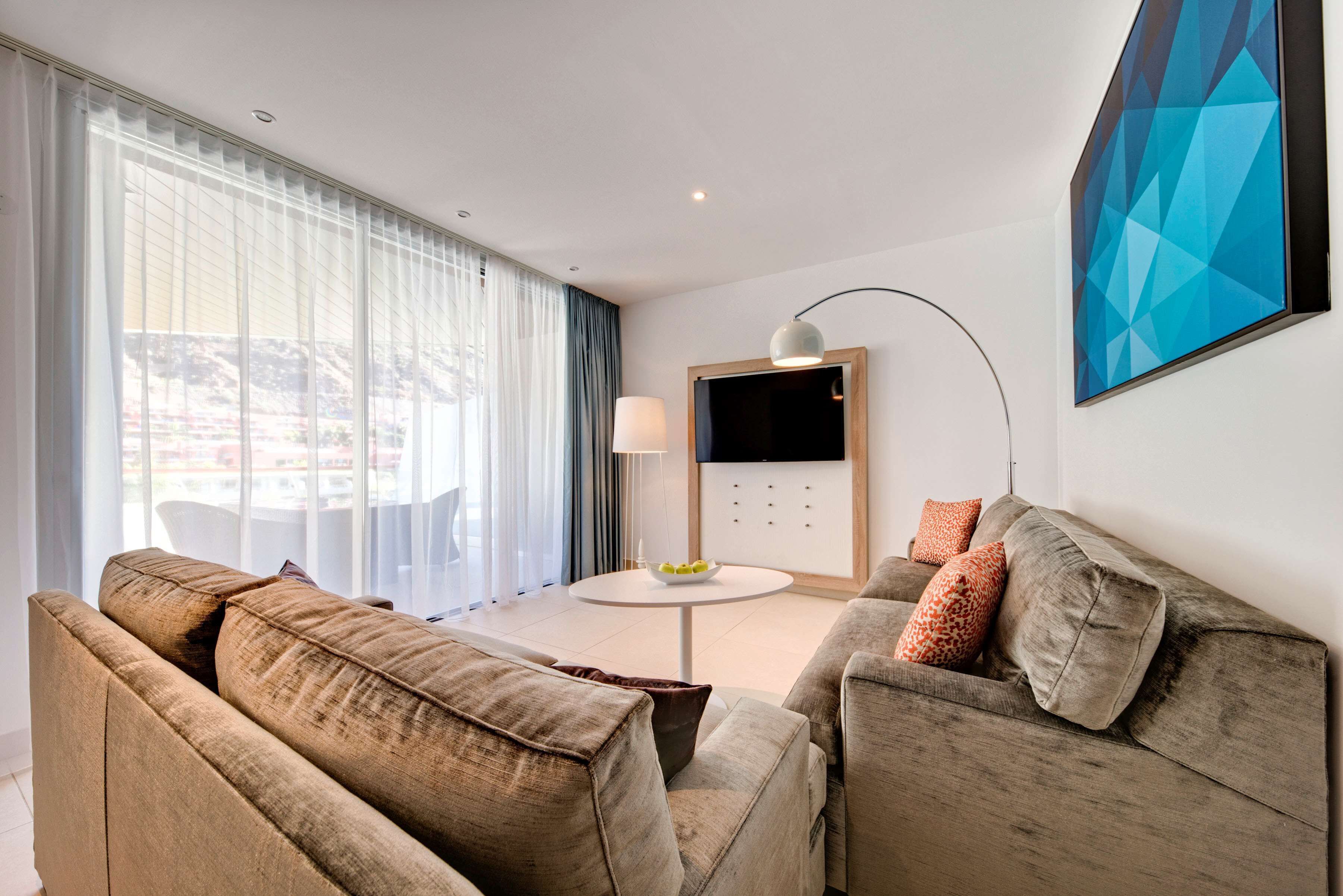 A modern living room with a sofa, a round table, and a TV.