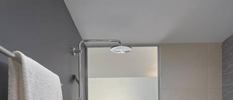 Un baño moderno con ducha de vidrio, una bañera blanca y una toalla colgada en un perchero.