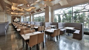 A modern restaurant with high ceilings, geometric light fixtures, and large windows offering views of the outdoors. - Royal Gold Hotel (Kaohsiung)