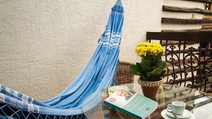 Un hamac, un livre, une plante en pot, une tasse et une soucoupe sur une table en verre.