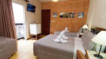 A hotel room with a bed, a small desk, a television, and a wall with pictures.