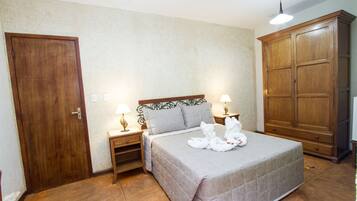 A bedroom with a bed, two bedside tables with lamps, a wardrobe, and a door.
