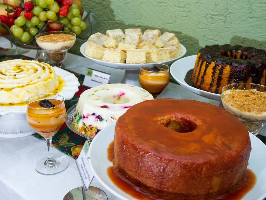 Une table où sont présentés divers desserts, notamment un flan au caramel, un gâteau au citron et un gâteau en forme de couronne.