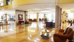 A spacious lobby with a polished floor, a seating area with a sofa and armchairs, and a reception desk. - Regina Hotel Pemalang (Pemalang)