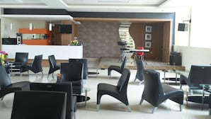 A modern hotel lobby with a reception desk, seating area, and a staircase leading to an upper level. - Regina Hotel Pemalang (Pemalang)