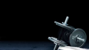 A 2.5 kg dumbbell with a flat, round weight plate and a slotted barbell resting on a dark surface.