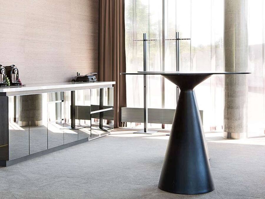 A modern interior with a central table, a counter with appliances, and large windows.
