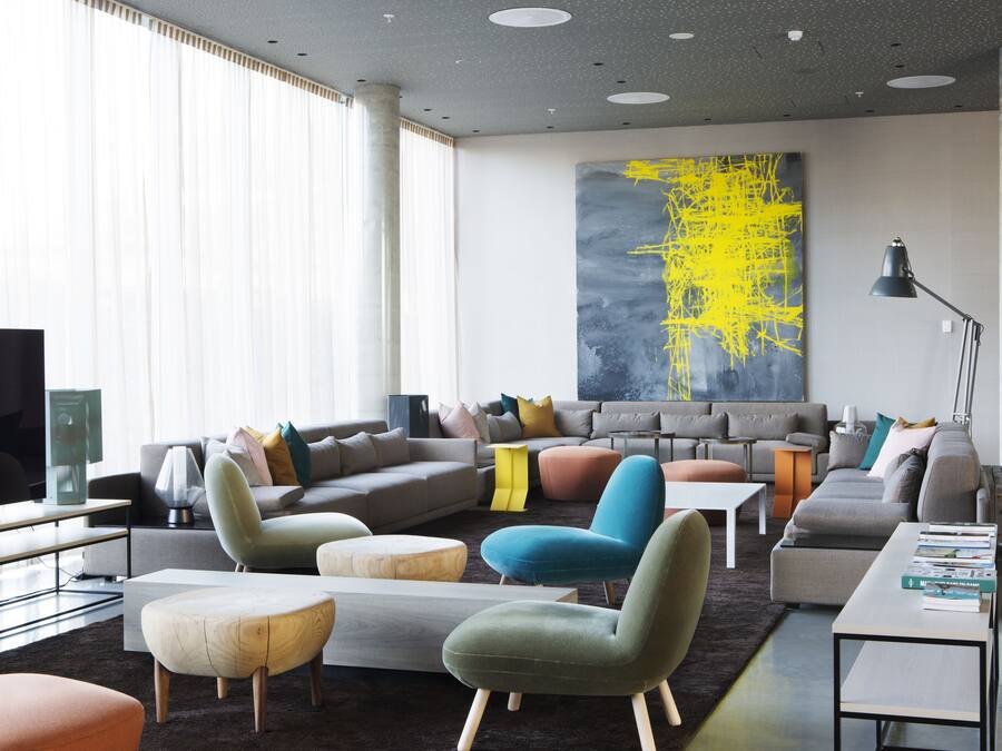 A modern living room with a sectional sofa, ottomans, a coffee table, and a large abstract painting on the wall.