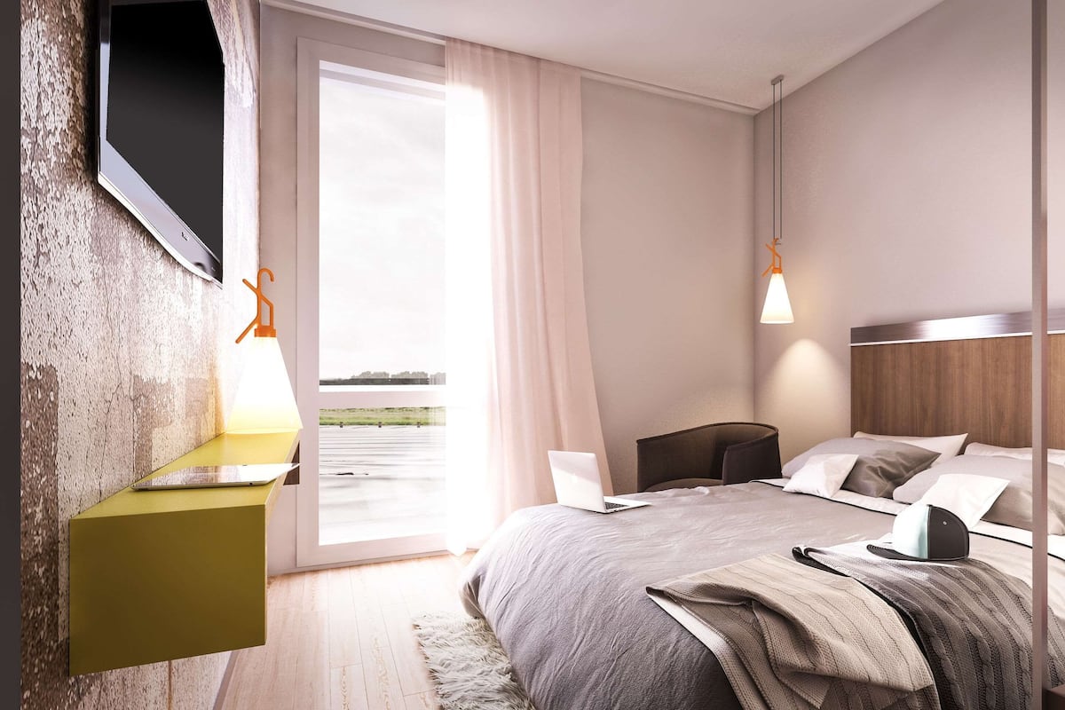 Un dormitorio moderno con cama, mesita de noche y una computadora portátil.