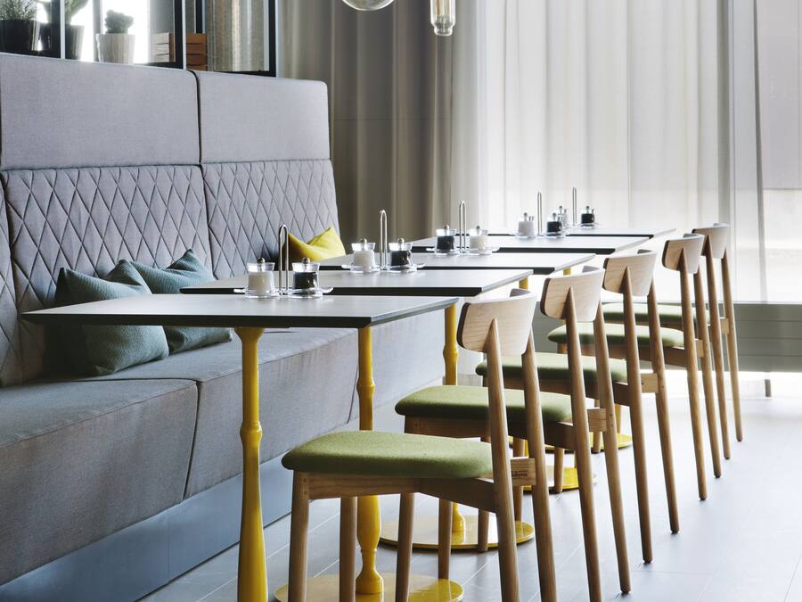 A modern dining area with a long table, chairs, and a sofa.
