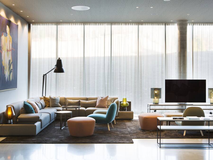 Un salon moderne avec un canapé, des poufs, une table basse, un téléviseur et un tableau accroché au mur.