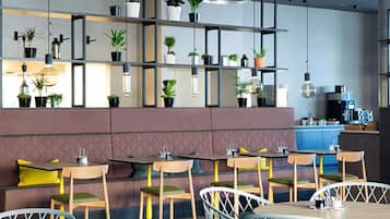 Um restaurante moderno com mesas e cadeiras de madeira, um banco acolchoado e prateleiras com plantas em vasos.