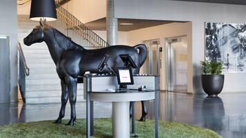 A modern lobby with a horse statue, a digital kiosk, and a staircase.