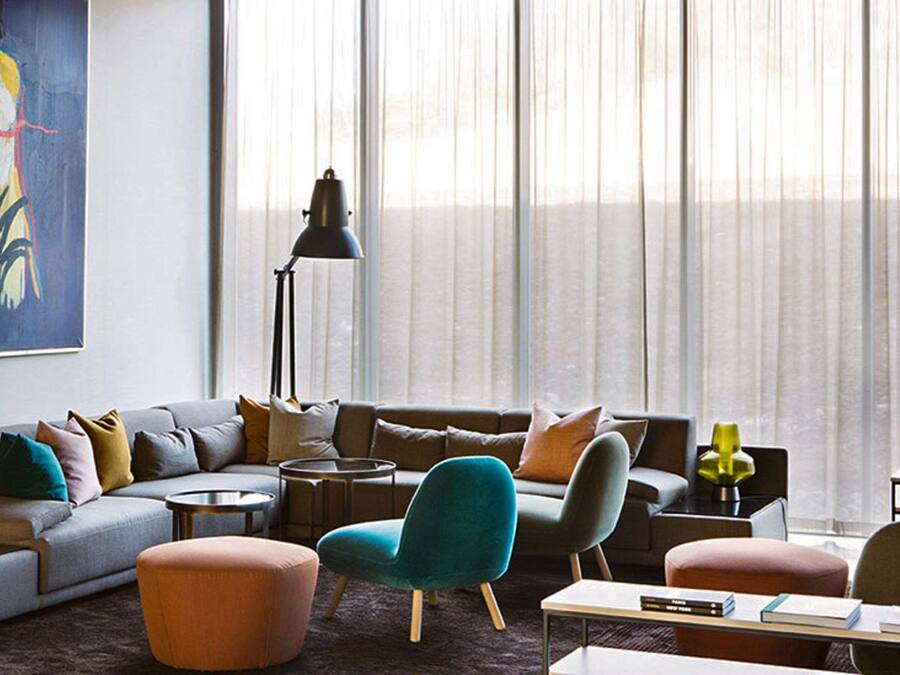 A modern living room with a grey sofa, teal armchair, and ottoman, a round coffee table, and a floor lamp.