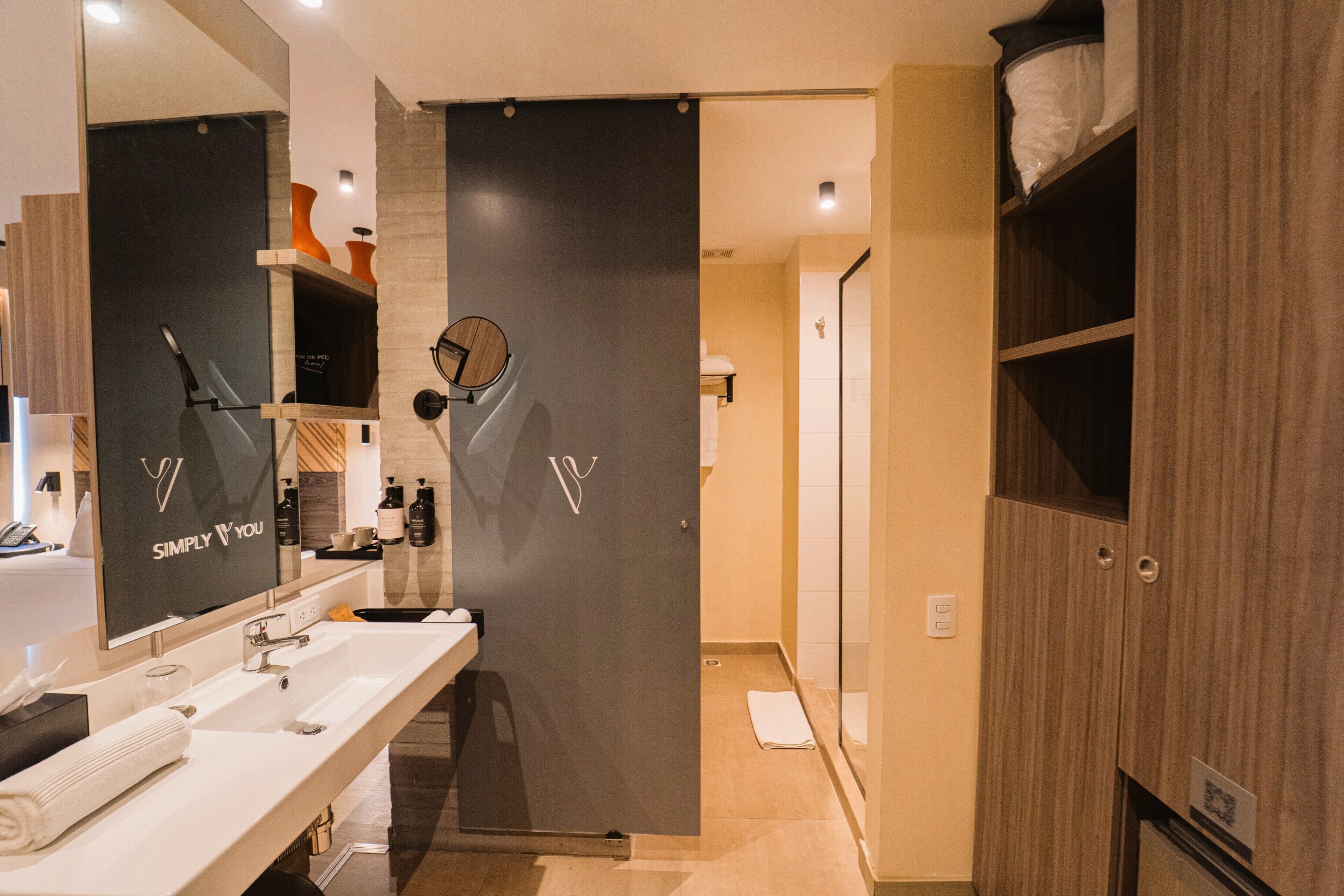 A modern bathroom with a large mirror, two sinks, and a dark partition.