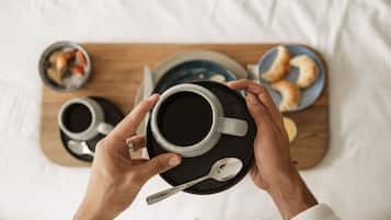 A person holding a cup of coffee with a spoon on a tray.