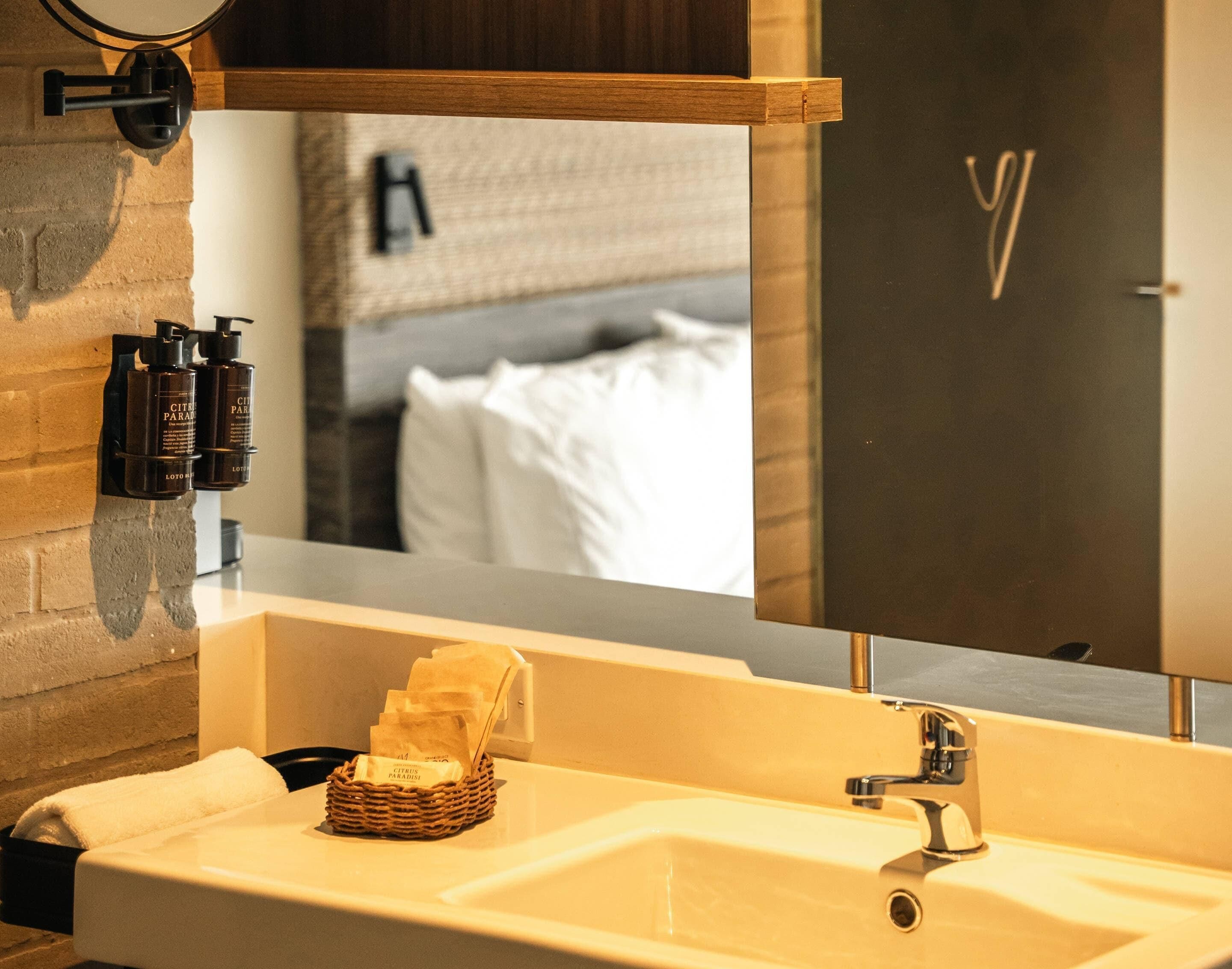 A bathroom with a sink, mirror, and toiletries.