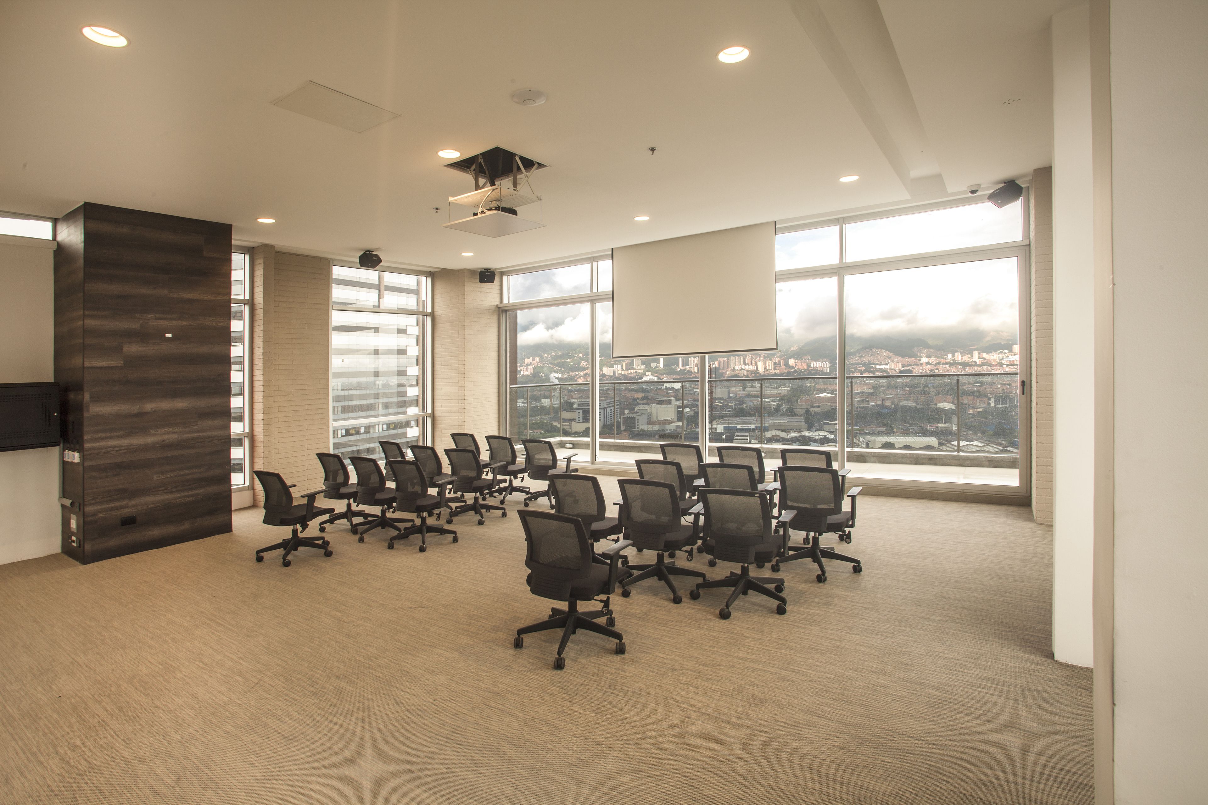 A conference room with a city view, large windows, and modern office chairs.