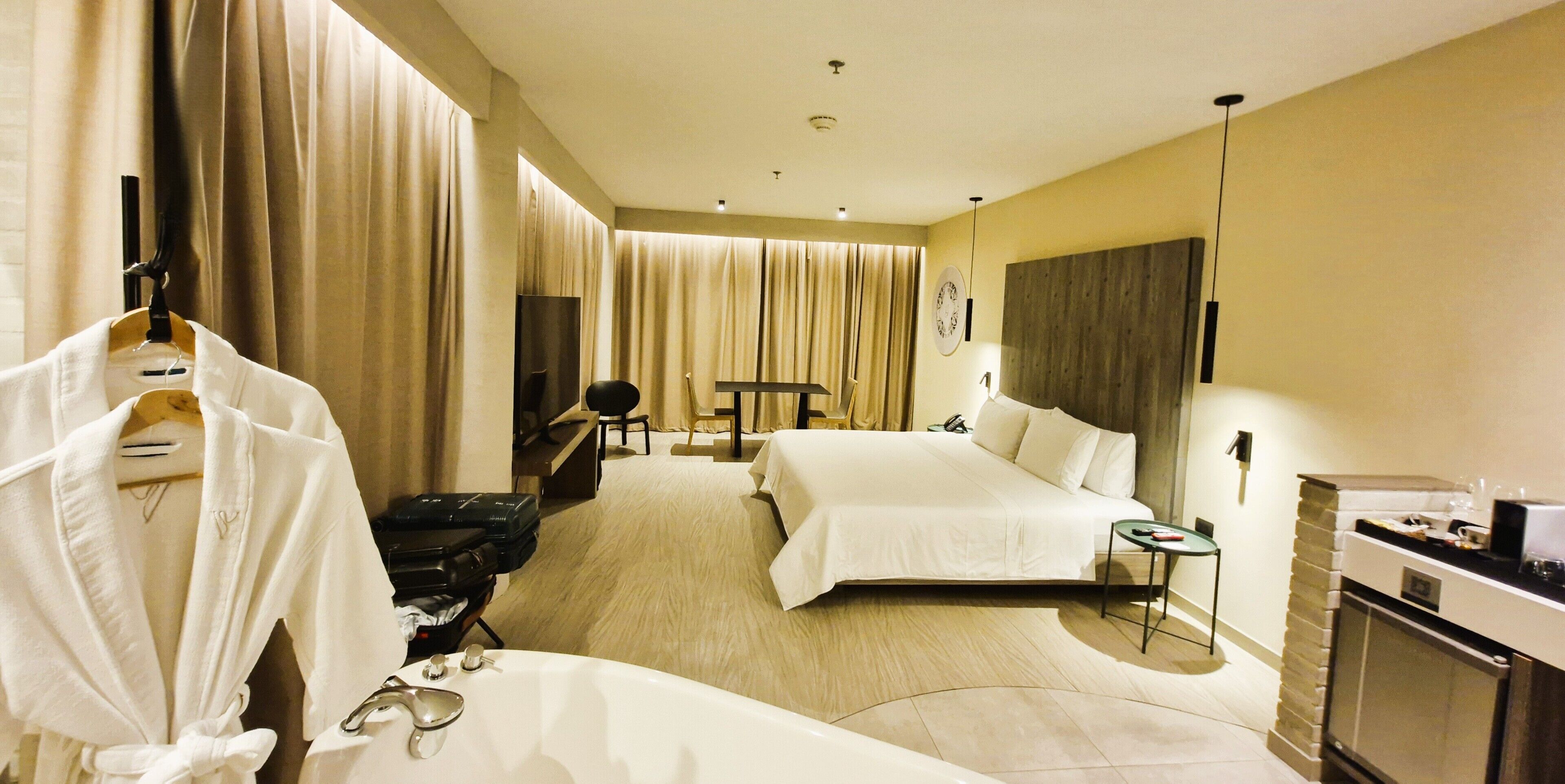 A hotel room with two beds, a desk, a chair, a TV, a minibar, and a bathroom.