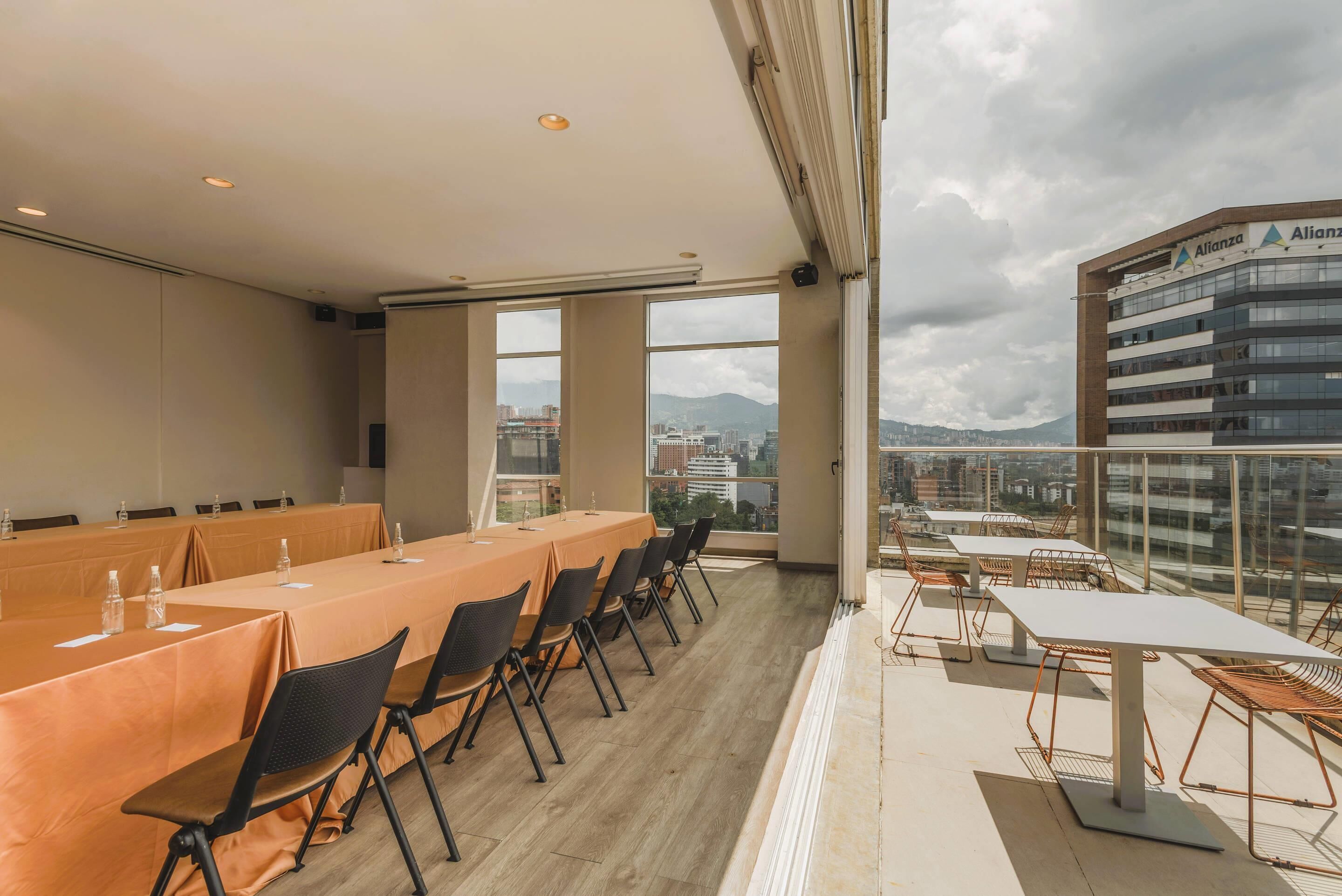 A conference room with tables and chairs, large windows, and a view of a cityscape.