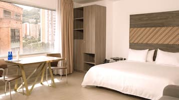 Habitación de hotel con cama, escritorio con sillas, teléfono y vistas a edificios.
