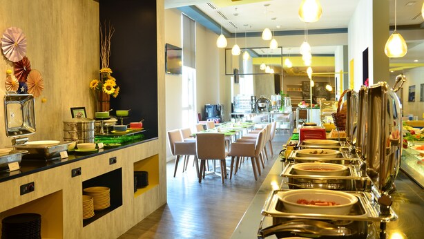 Een buffetopstelling met meerdere bedieningspunten, een zithoek met stoelen, en een modern interieur.
