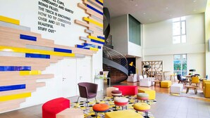 Een modern interieur met een trap, kleurrijke muurdecoratie en verschillende zitmogelijkheden.