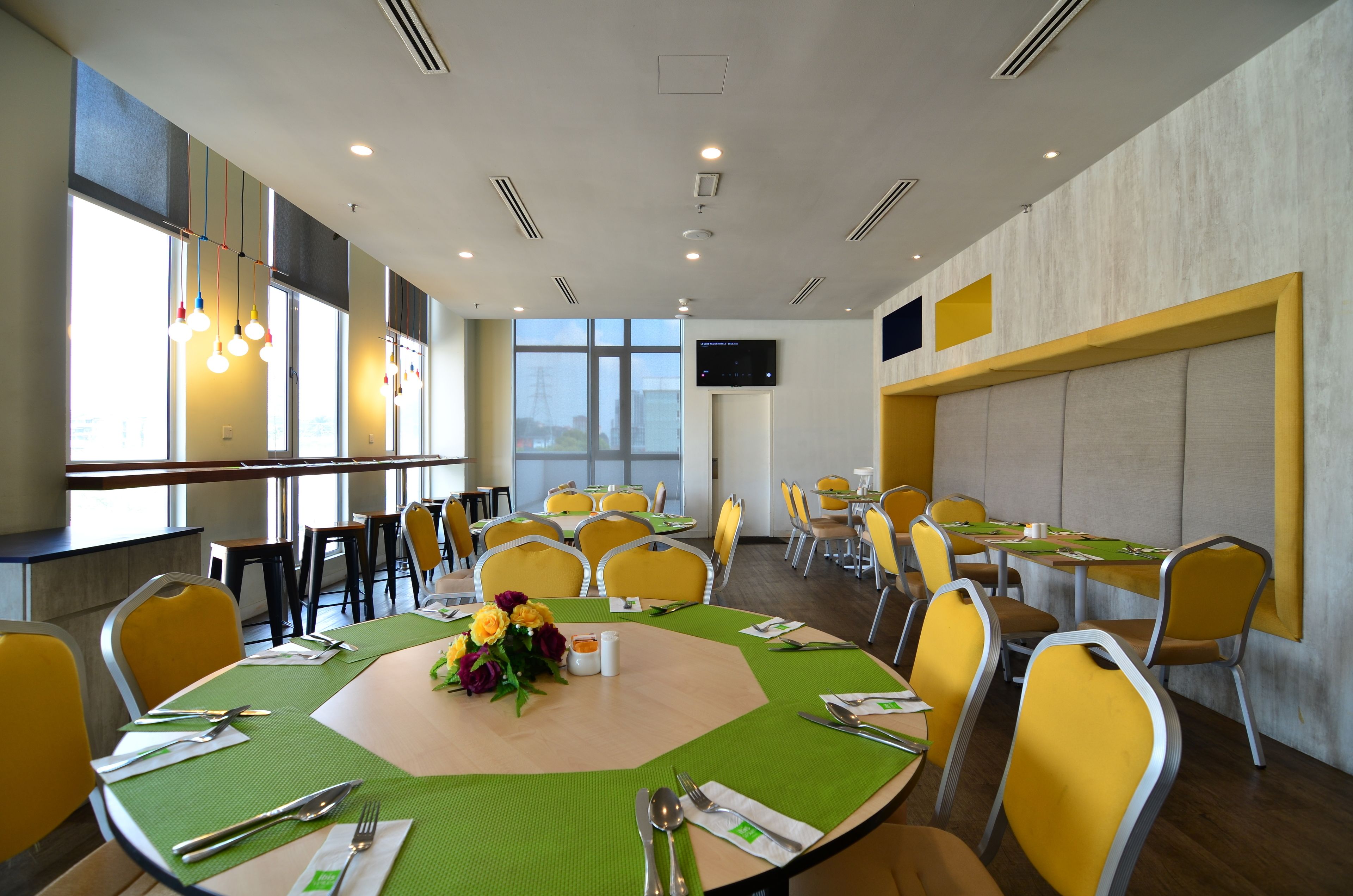 A conference room with round tables, yellow chairs, and a large window with a city view.