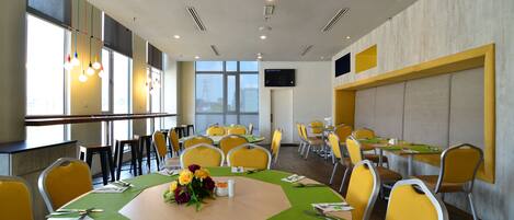 A conference room with round tables, yellow chairs, and a large window with a city view.