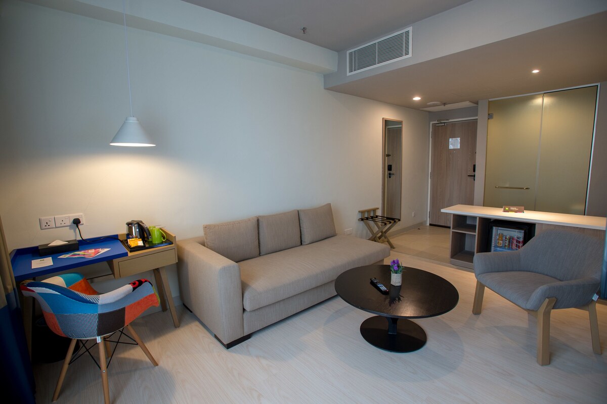 Una sala de estar moderna con un sofá, una mesa de centro, un escritorio con una silla y un mueble para la televisión.