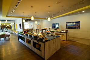 A buffet area with multiple serving stations, a central island with food items, and a seating area with tables and chairs.