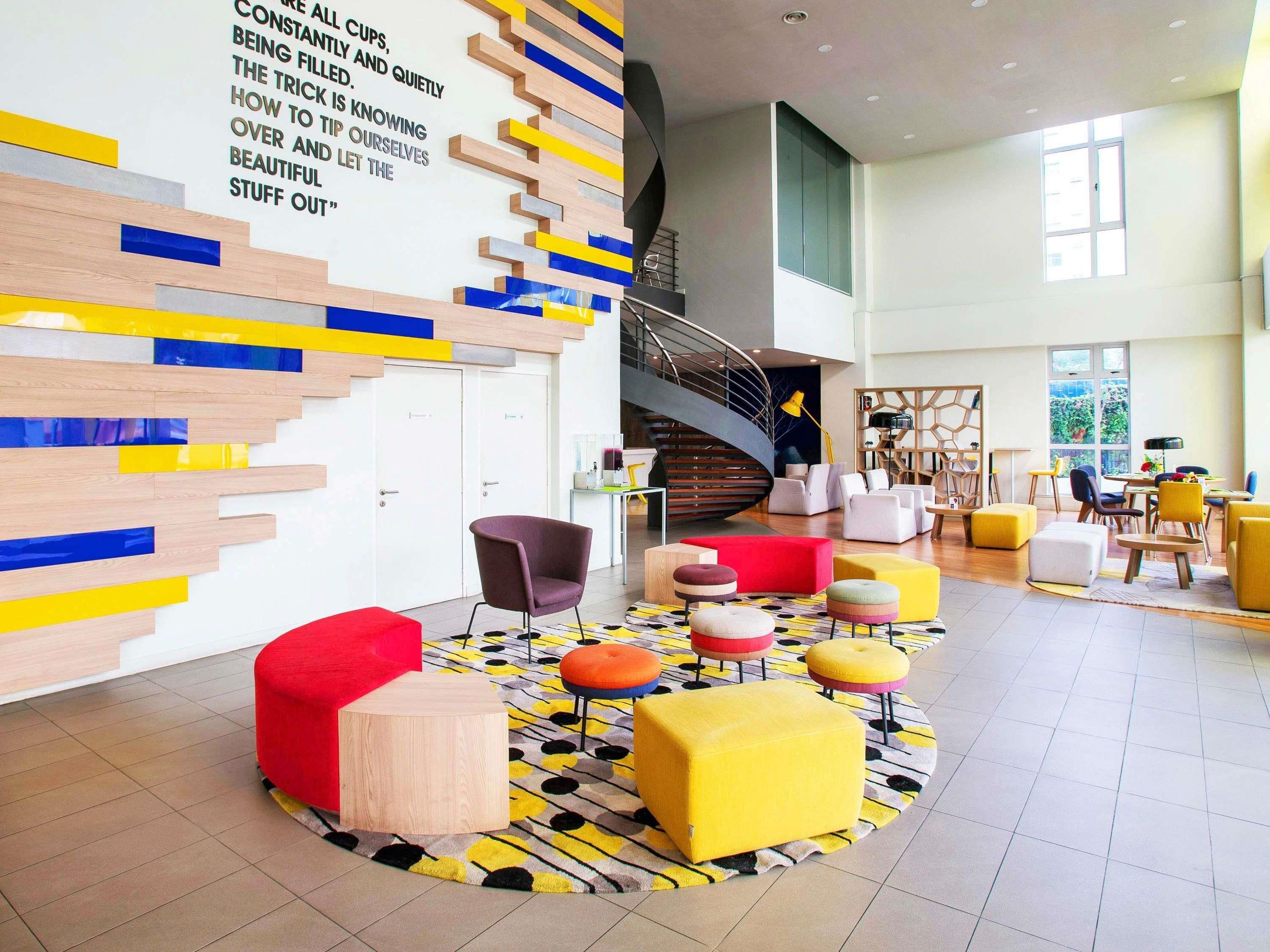Een modern interieur met een trap, kleurrijke muurdecoratie en verschillende zitmogelijkheden.